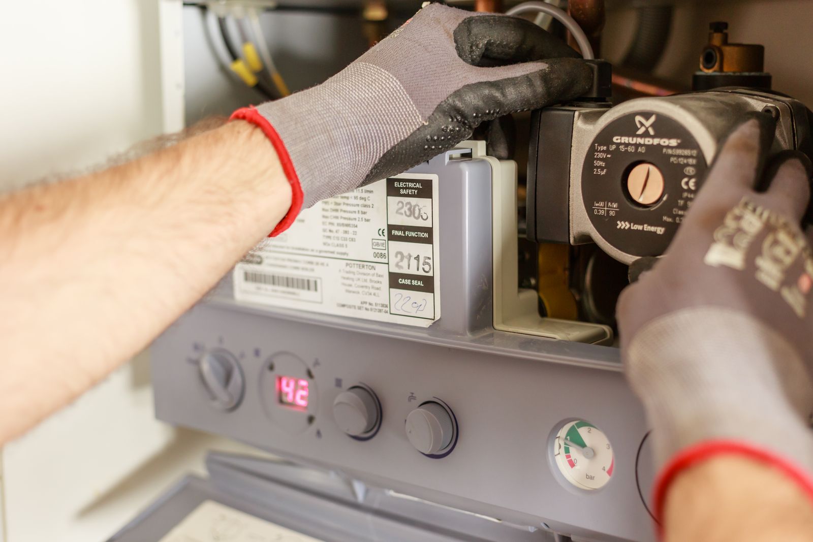 Mains d'un technicien réglant une chaudière lors d'un entretien