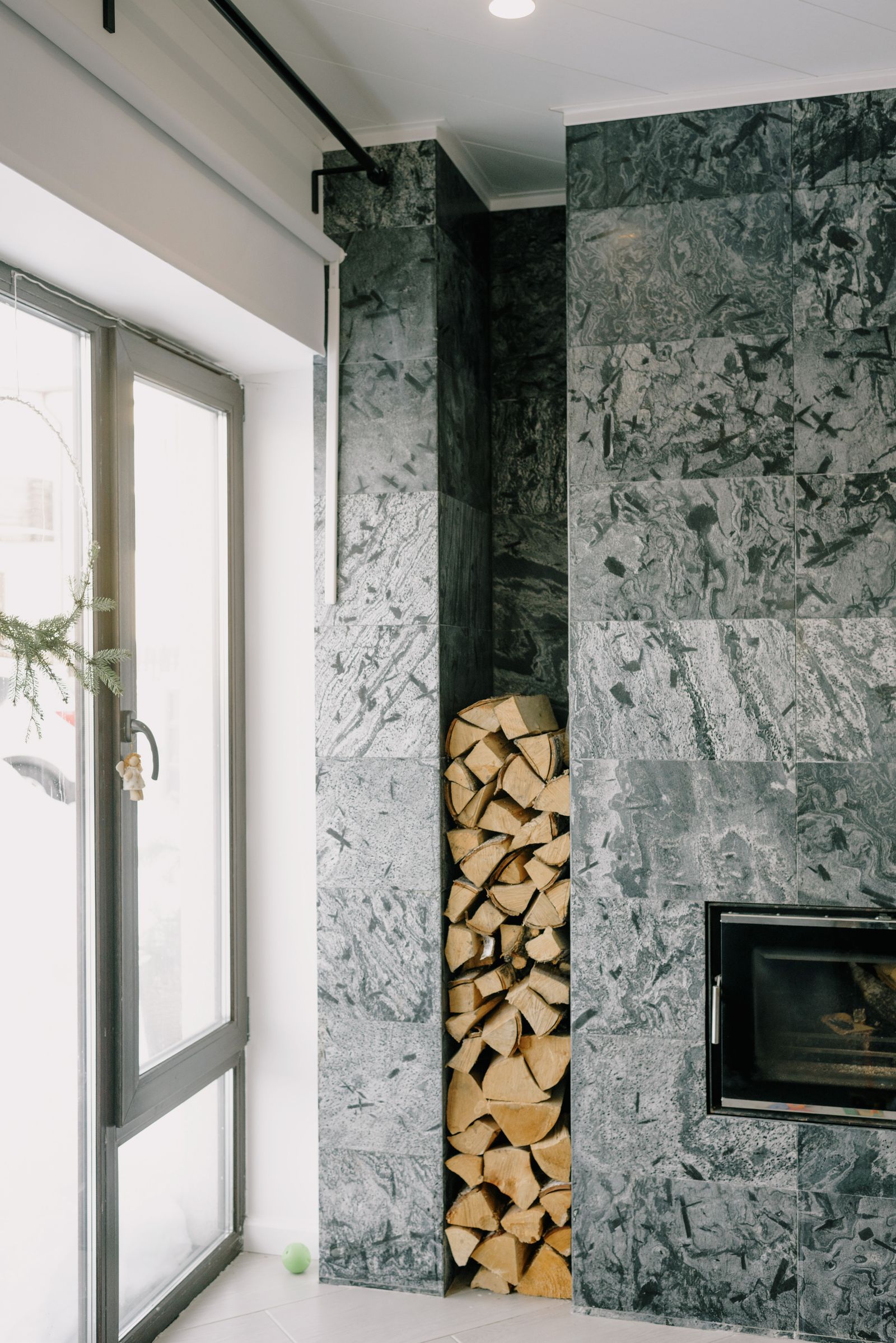 Cheminée habillée de pierre avec réserve de bois dans un salon moderne